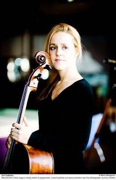 a woman holding a violin in her right hand and looking at the camera with an intense look on her face