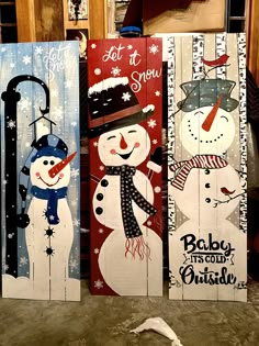 three snowmen are painted on wooden boards