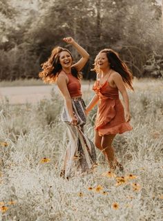 two young women are walking through the tall grass