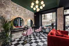 a salon with checkered floor and red chairs in front of two large windows that look out onto the street