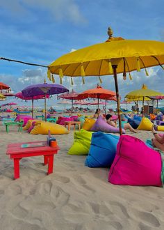 many colorful pillows and umbrellas on the beach