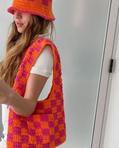 a woman wearing an orange and pink crocheted bag