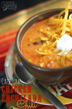 a bowl of chicken enchilada chili with sour cream and tortilla chips