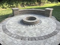 a brick fire pit surrounded by grass and trees