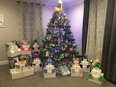 a decorated christmas tree in a living room with presents under it and other decorations on the floor