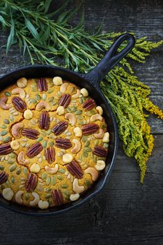 a skillet filled with food sitting on top of a table next to some plants