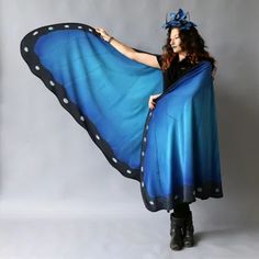 a woman wearing a blue butterfly cape with polka dots on the bottom and black wings