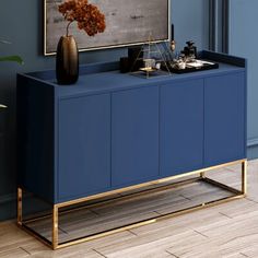 a blue sideboard with gold legs and a painting on the wall