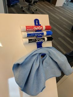 three markers, one blue and one red are on the back of a white chair