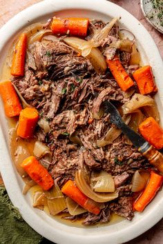 a white bowl filled with meat and carrots on top of a pink table cloth