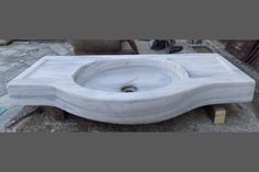 a white sink sitting on top of a stone slab