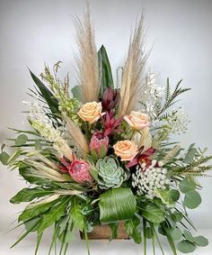 an arrangement of flowers and greenery in a wooden box