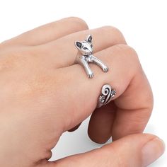 a person's hand holding a silver ring with a cat on it