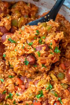 a spoon full of rice with sausage and peppers