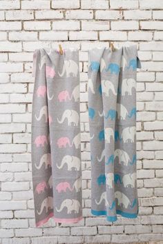 two towels hanging on a clothes line in front of a brick wall with elephants printed on them