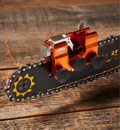 an orange bike chain on top of a wooden table with chains attached to the end