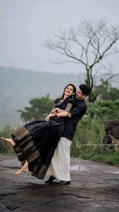 a man carrying a woman on his back while walking down a road in the rain