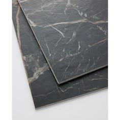 two pieces of black marble with gold veining on the top and bottom, laying next to each other