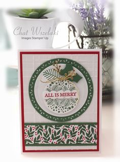 an all is merry card on a table next to a potted plant and vase