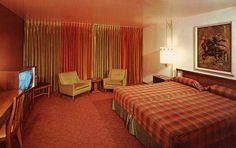 a hotel room with a bed, chair and television in it's center area