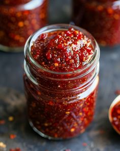 a jar filled with red sauce sitting on top of a table next to other jars