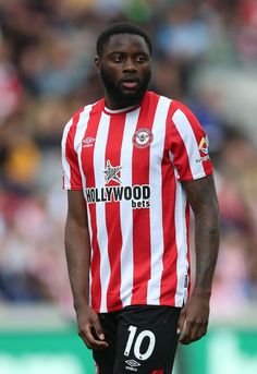 a man standing on top of a soccer field wearing a red and white striped shirt