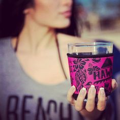 a woman holding up a cup with the word hawaii on it in front of her face