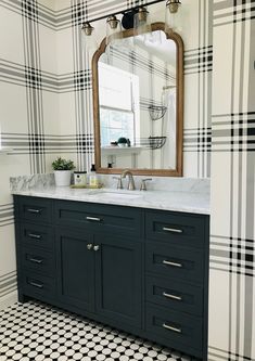 a bathroom with black and white checkered wallpaper, a large mirror above the sink