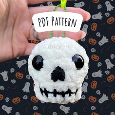 a hand holding a small white skull with a tag that says pdf pattern on it