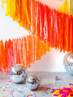 disco balls and streamers on the floor in front of a wall with confetti