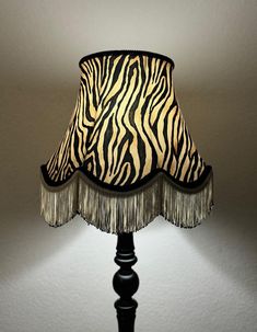 a lamp with a zebra print shade on it's bottom and fringe trim around the base