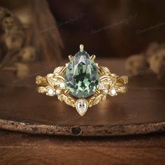 a ring with a green stone surrounded by leaves and diamonds on a wooden table top