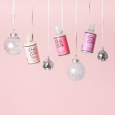 five christmas ornaments hanging from strings on a pink background