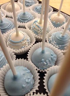 there are many blue and white cake pops on the tray with some candles in them