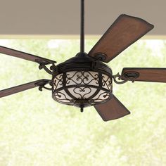 a ceiling fan with a light on it in front of a large window and green grass