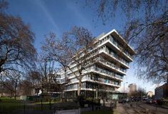 an apartment building with many balconies on the top floor and trees in front of it