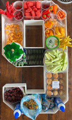 a number shaped food tray filled with fruits and veggies on top of a wooden table