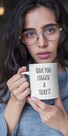 a woman holding a coffee mug with the words i have you logged at ticket?