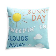 a blue pillow with the words sunny day on it and clouds in the sky above