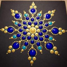 a blue and gold snowflake is shown on a black surface with golden dots