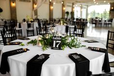 the table is set with black and white linens, greenery and candle holders