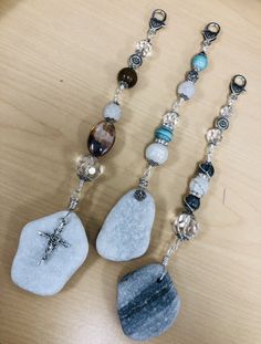 two necklaces with beads and charms on them sitting on a table next to each other