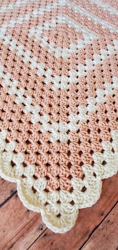 an orange and white crocheted blanket sitting on top of a wooden floor