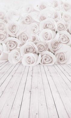 a bunch of white roses sitting on top of a wooden floor