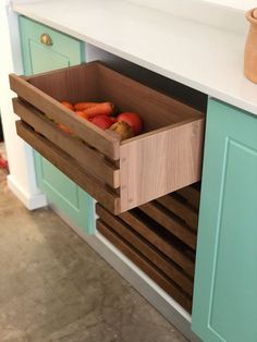 a wooden box filled with vegetables on top of a kitchen counter next to blue cabinets