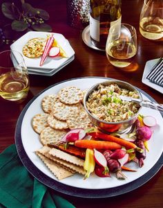 a plate with crackers, carrots, celery and radishes on it