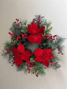 a christmas wreath with poinsettis and greenery