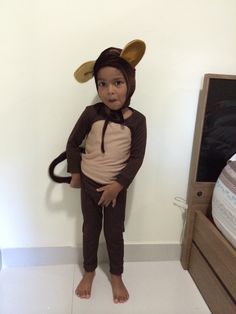 a young child dressed in a monkey costume standing on a white floor next to a tv