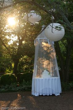 a canopy bed with two lamps hanging from it's sides in front of trees