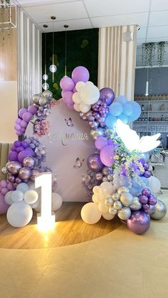 an arch made out of balloons and flowers with the number one in front of it